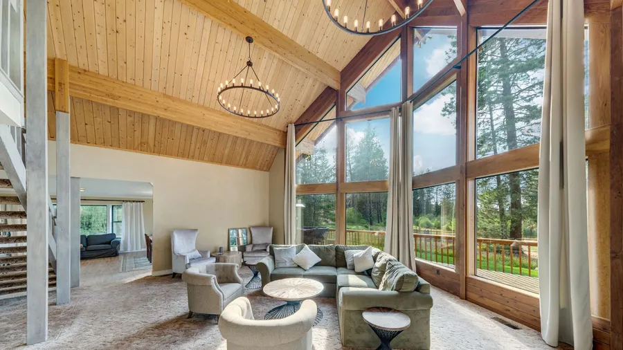 Grant huge living room with and three story tall windows in an amazing luxury room with open staricase and wooden vaulted ceiling.