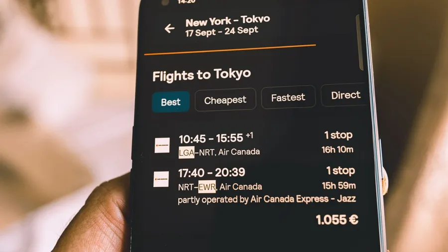 madrid, spain 28-10-2024: looking for flight tickets to Tokyo from New York on mobile phone