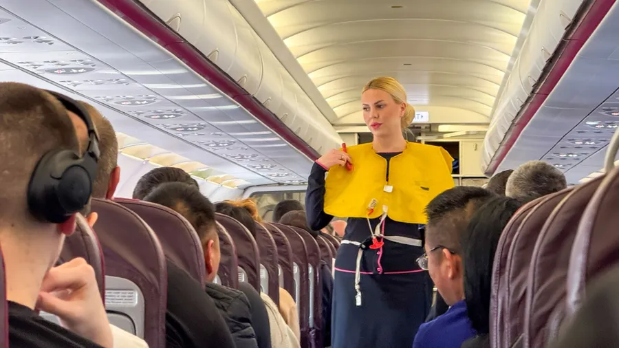 Blonde woman demonstrates safety vest, aviation serenity ritual, World Aviation Day, skyward journey charm April 5 2025, Barcelona, Spain