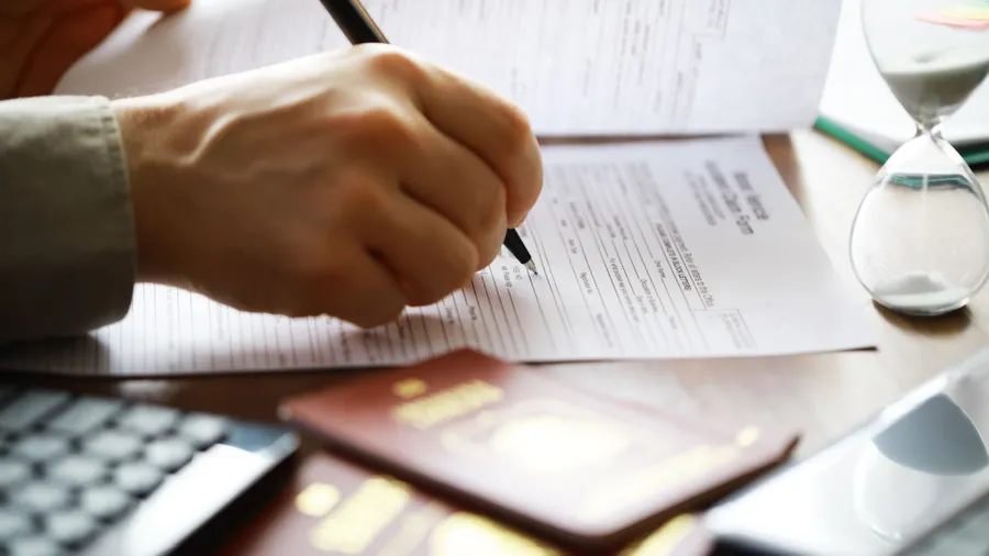 Filling Out Application Form with Passport and Hourglass - Immigration and Documentation Concept