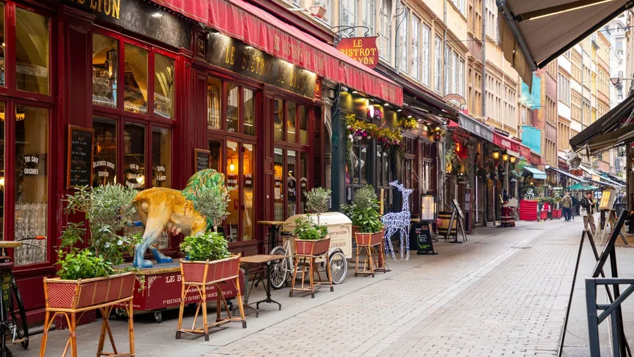 Colorful French bistro street with red awnings, festive decorations, outdoor seating, and cobblestone charm.