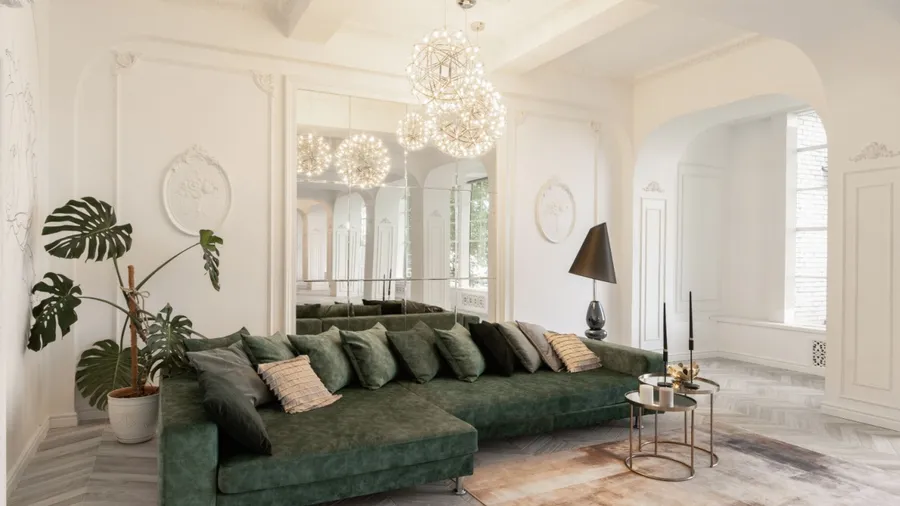 A chic lounge with a green sectional sofa, elegant lighting, and decorative mirrors.