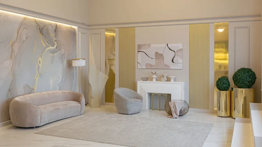 A wellness room interior with a cozy sofa, armchair, rug, plants, and abstract artwork on a warm beige wall.