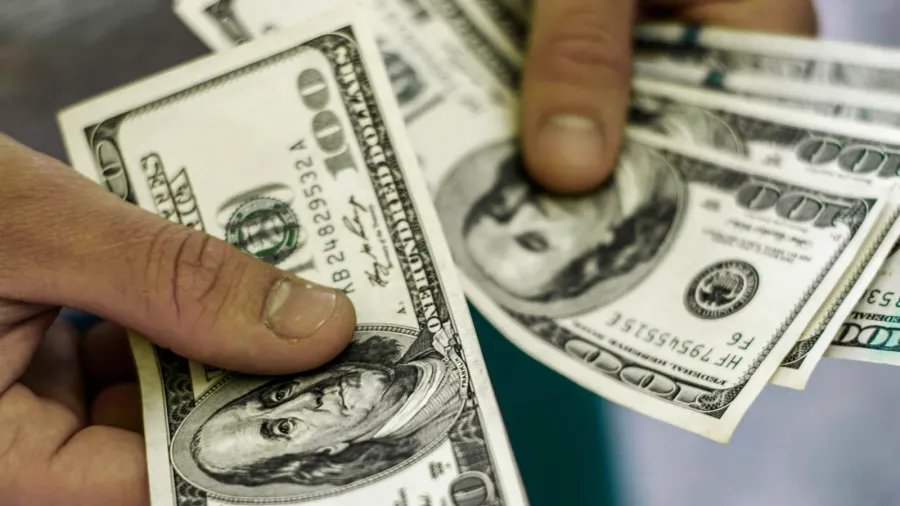 a man counts money a bundle of hundred dollar bills