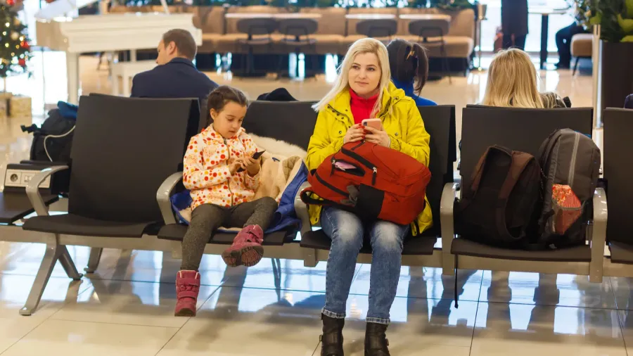 adorable toddler girl and her mom waiting at the airport