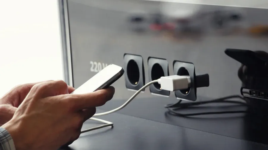 airport public charger and mans hands with smartphone airplane in