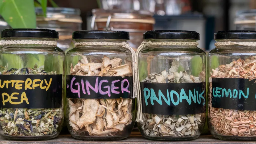 assortment of dried spices in glass bottles on wooden background