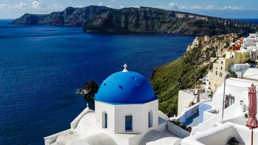 bluedomed church near white houses and sea in santorini