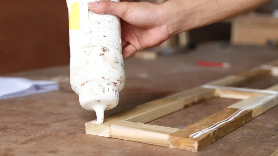 carpenter putting glue on a piece of wood