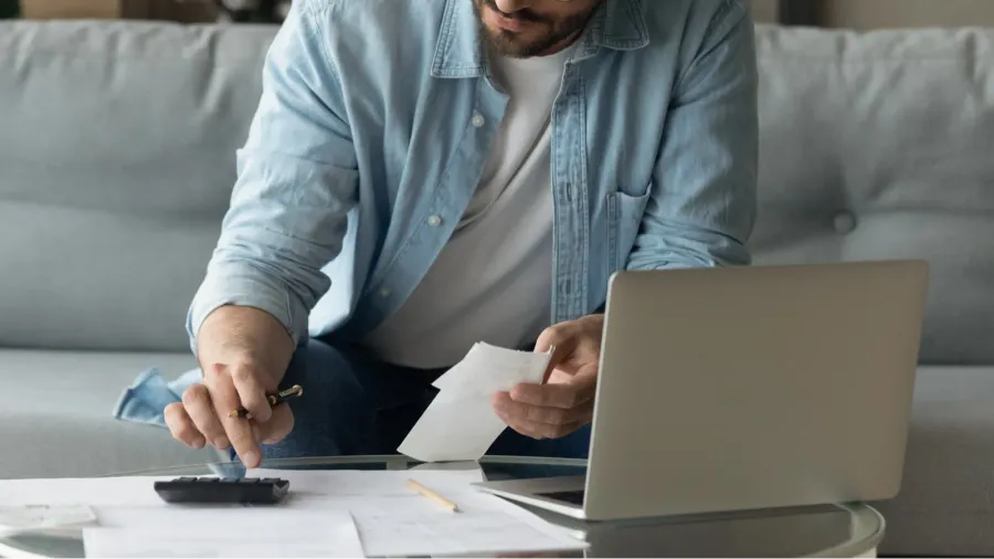 concentrated young 30s man in eyeglasses calculating expenditures