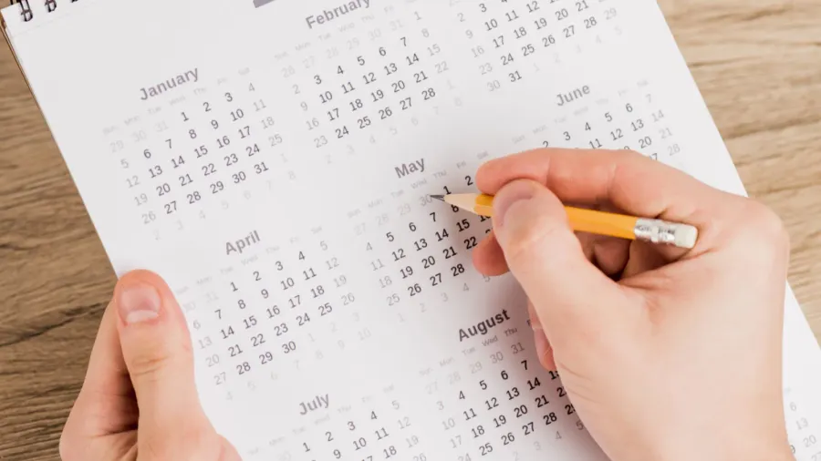 cropped view of man noting date with pencil on calendar