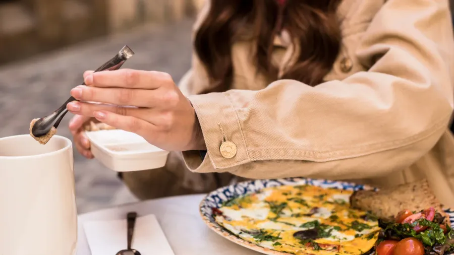 cropped view of woman putting sugar cube in cup of