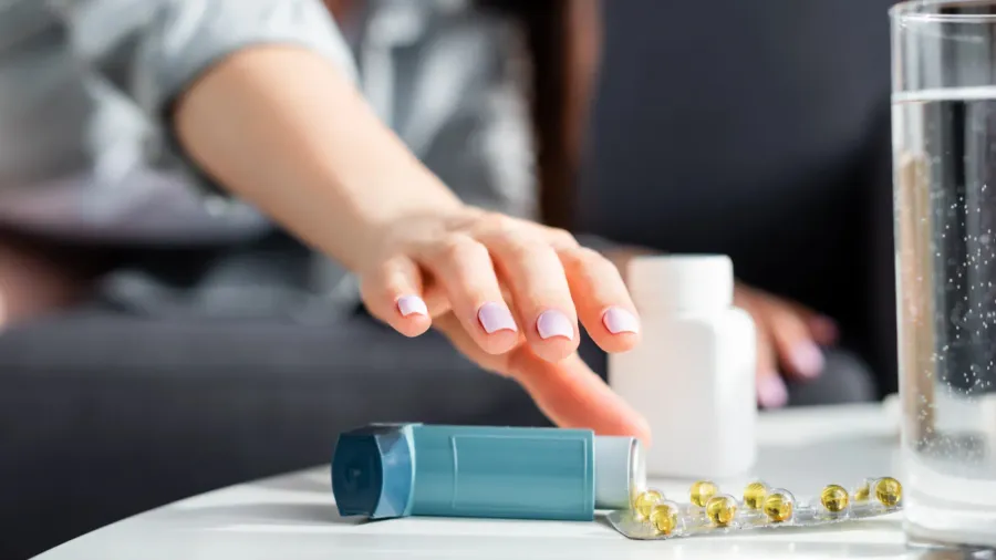 cropped view of woman reaching for inhaler on coffee table
