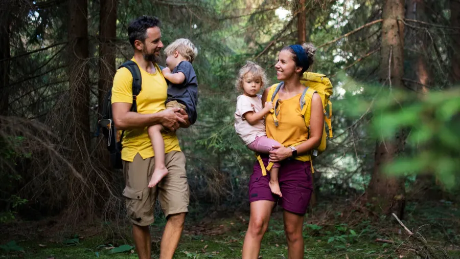 family with small children walking barefoot outdoors in summer nature