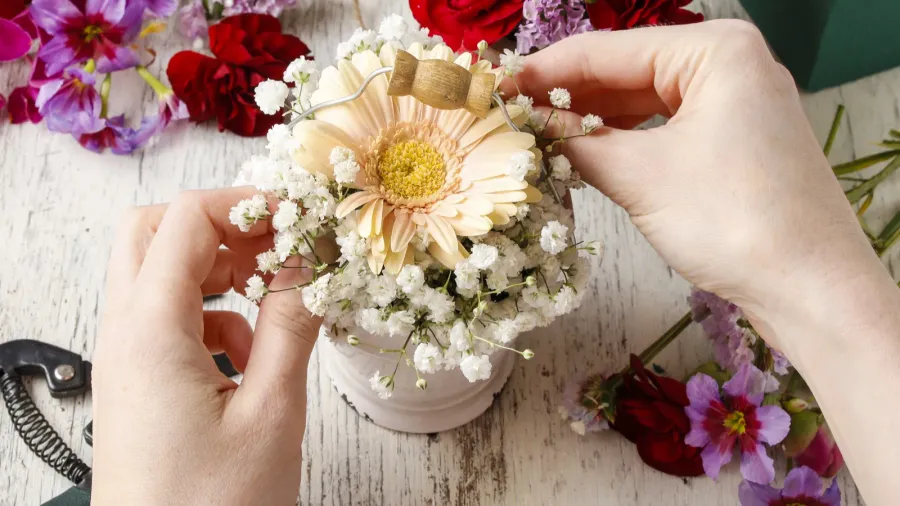 Arrangement of hands holding a small flower bouquet.