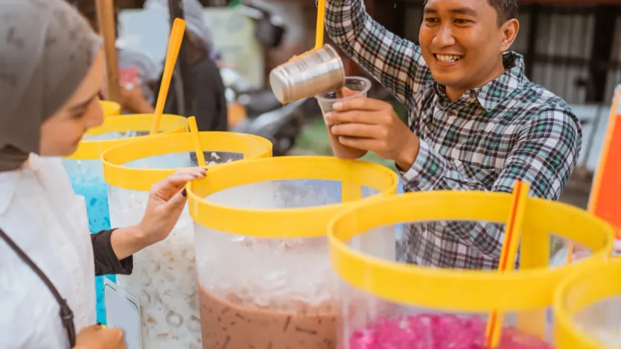 man sells colorful drink and juice in a jar to