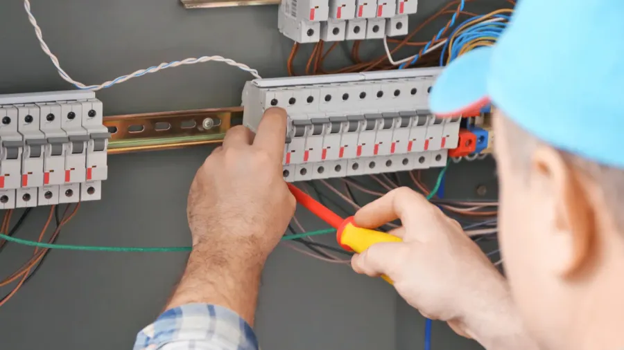 mature electrician repairing distribution board
