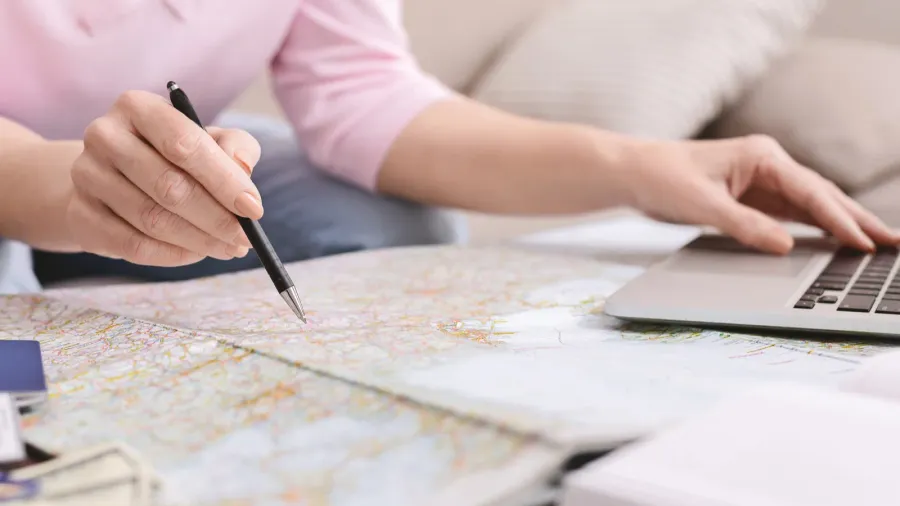 retired woman planning her worldwide trip with map and laptop