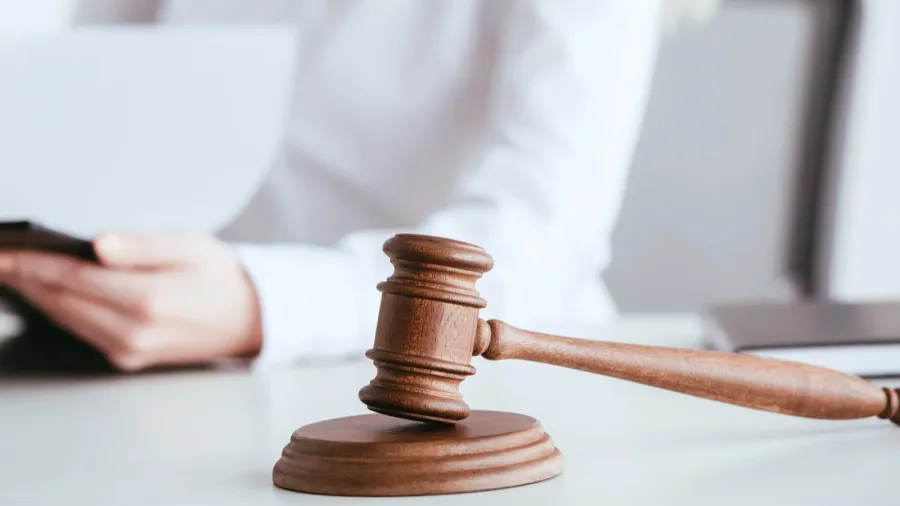 selective focus of gavel near woman holding clipboard with document