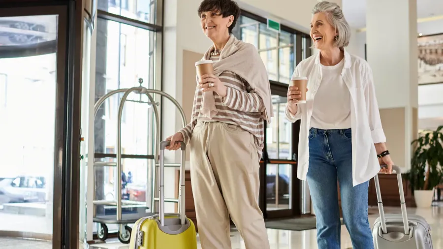 senior lesbian couple with luggage standing affectionately