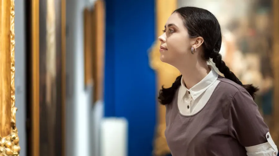 side view of young caucasian pretty woman contemplates ancient artefacts