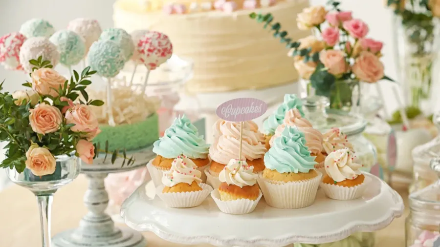 Beautiful pastel flowers on a dessert table with pastel topper on cupcake.
