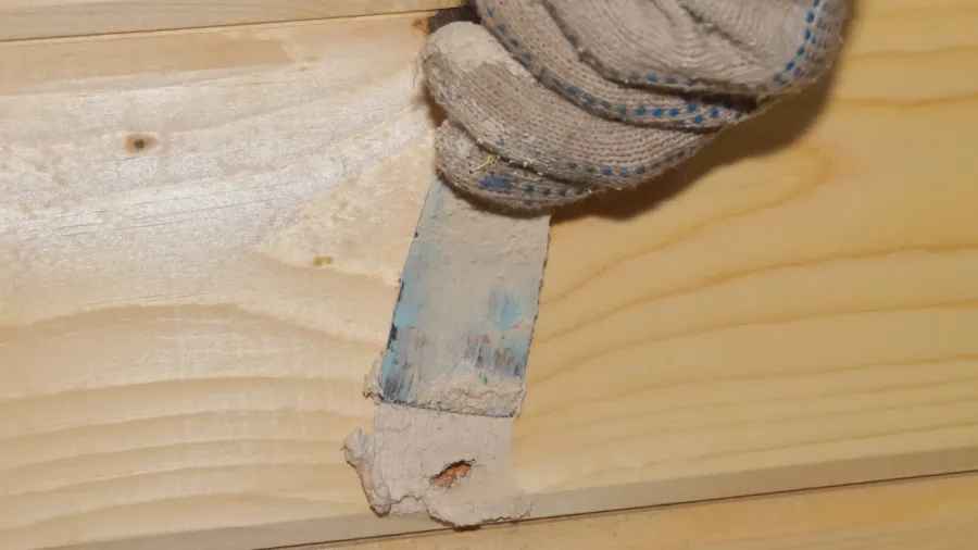 the worker puts putty on a hole in a wooden