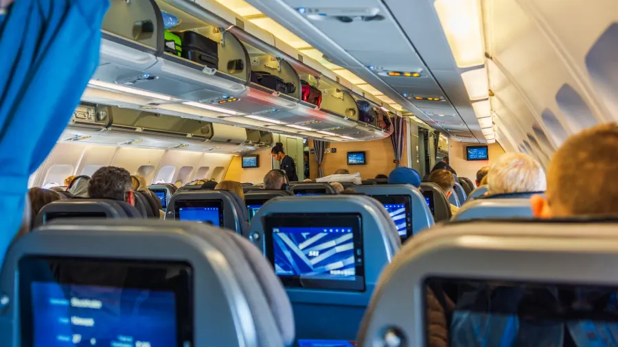 view of airplane economy class cabin showing passengers seated comfortably