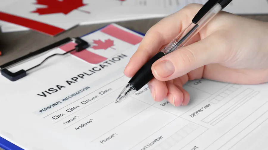 woman filling visa application form to canada at table closeup