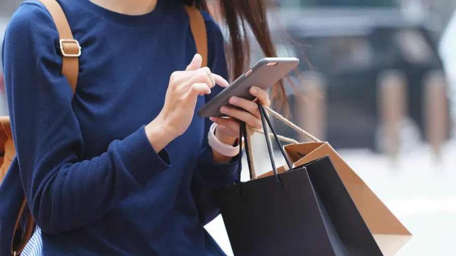 woman look at mobile phone and holding shopping bags