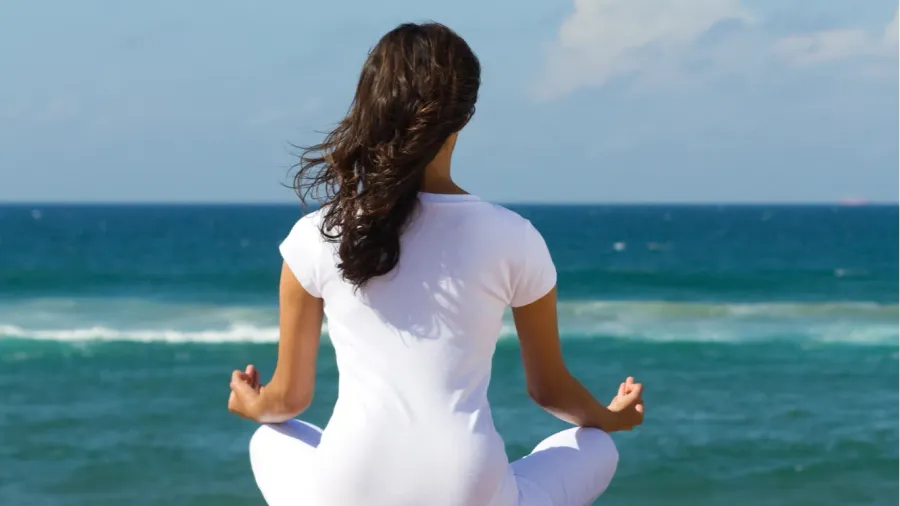 young beautiful woman meditation on beach