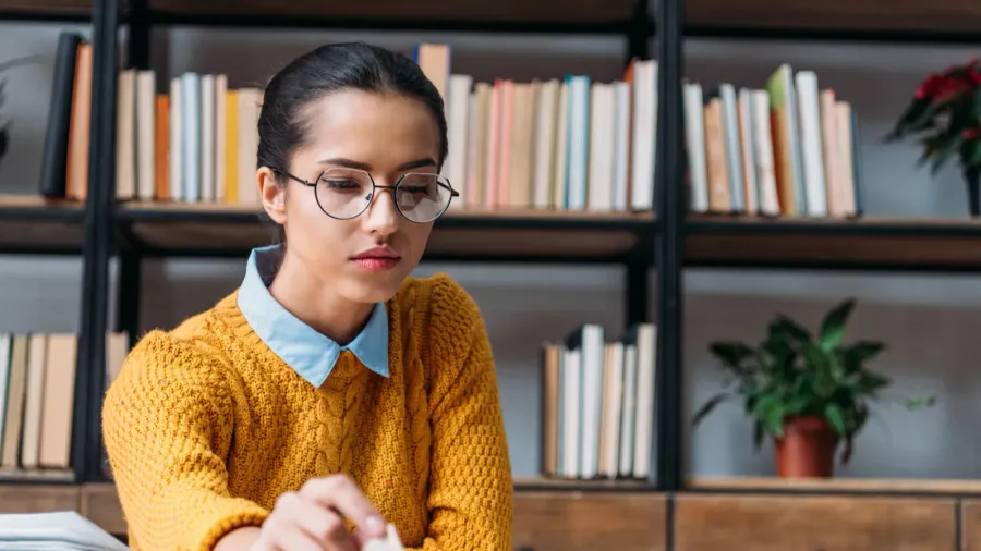young student girl preparing for exam at library and reading